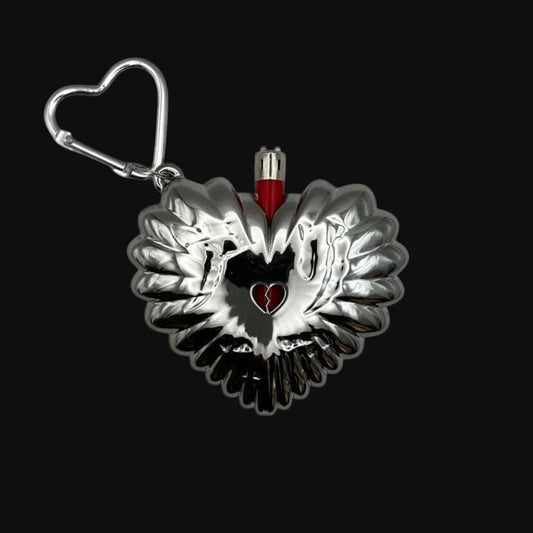 Chrome heart-shaped bic mini lighter case with a red lighter inside on a black background